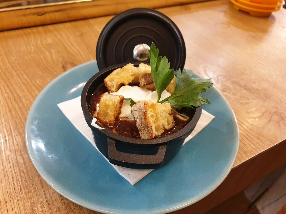 Soupe à l'oignon gratinée en petite cocotte, croûtons et persil.